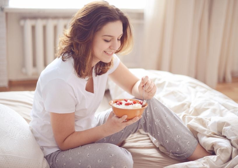 Frau isst Frühstück im Bett
