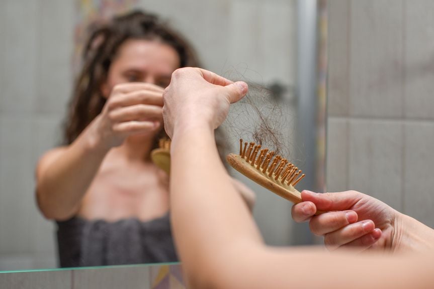 Frau zieht Haarbüschel aus der Bürste