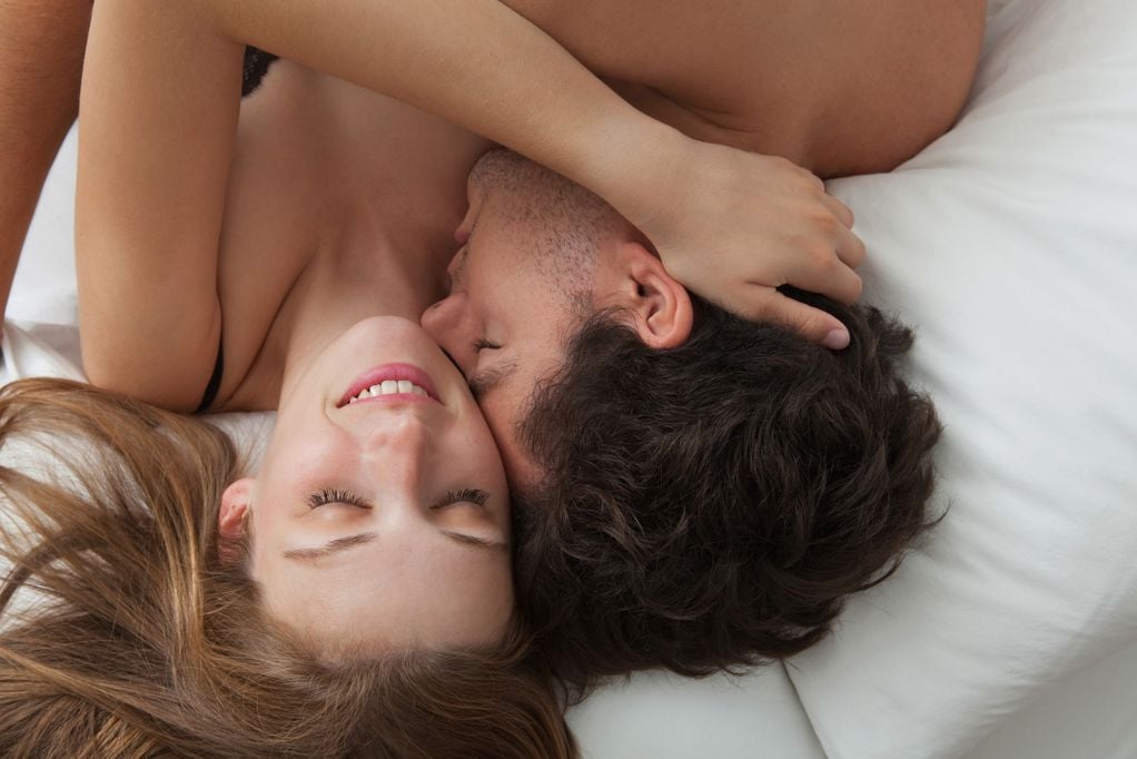 Paar kuschelt sich im Bett aneinander
